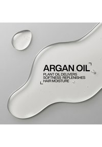 Clear liquid drops labeled argan oil with text stating it delivers softness and replenishes hair moisture on a light gray background.