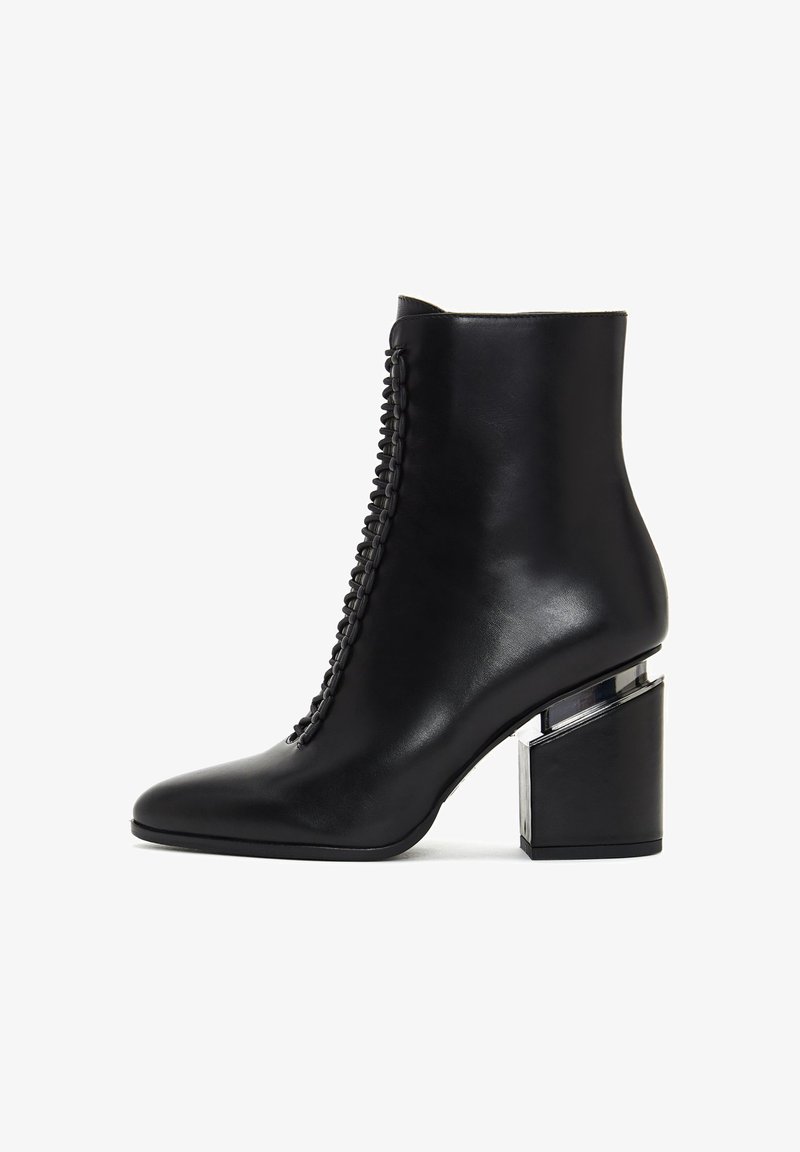 Botte cheville en cuir noir avec un détail tressé à l'avant et un talon bloc avec une accent métallique argenté.
