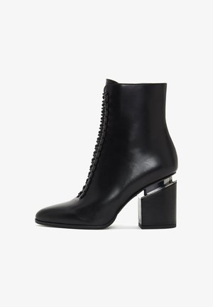 Black leather ankle boot with a pointed toe and chunky block heel. Features decorative lacing along the outer side. Smooth texture.