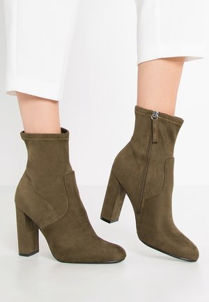 Braune Wildleder-Stiefeletten mit Blockabsatz, spitzer Zehenpartie und seitlichem Reißverschluss. Verfügt über gestickte Details entlang der Kanten und eine glatte Textur.