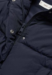 Navy puffer jacket with shiny metallic snaps, a zippered front, and a textured fabric. Features a smooth lining and insulated padding.