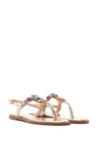 Sandalias planas metálicas doradas con adornos de joyería en azul y púrpura, con un diseño de tira para el dedo del pie y correas de tobillo ajustables.