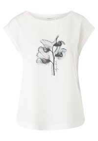 Weiße Bluse mit kurzen Ärmeln, die ein halbtransparentes schwarzes und graues Blumenmuster aufweist und den Schriftzug "Sweet Pea Flower" in der Mitte vorne trägt.