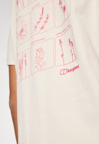 Svetlo béžové tričko s krátkym rukávom, ktoré obsahuje ružové botanické ilustrácie a logo "berghaus" v pravom dolnom rohu.