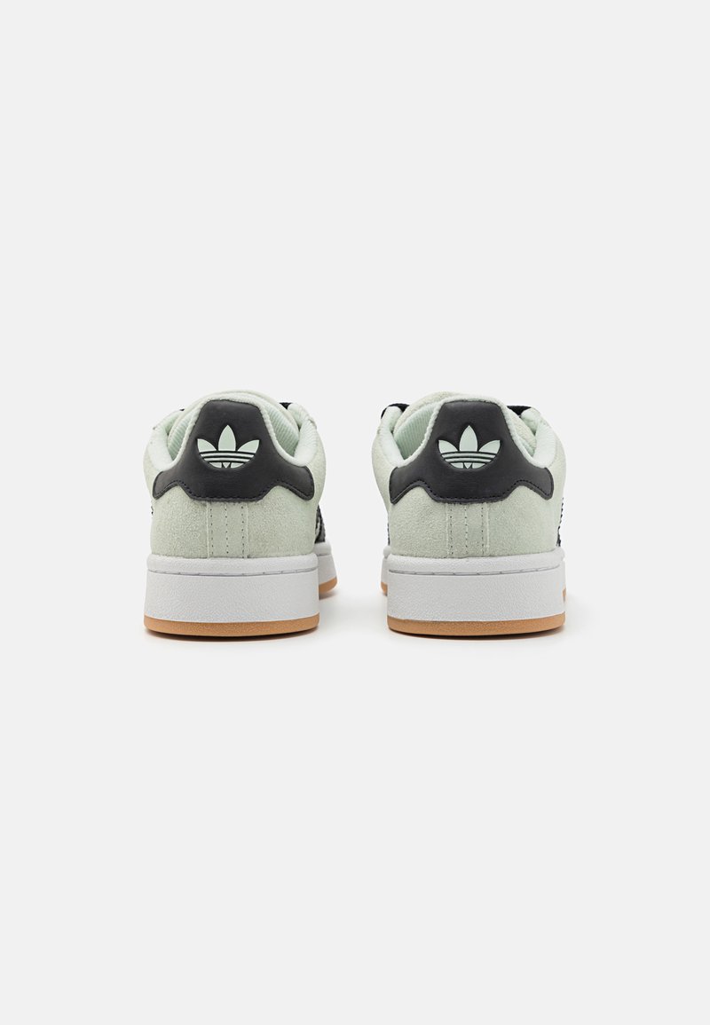 Sneakers in suede verde chiaro con dettagli neri, dotati di una suola intermedia bianca e suola in gomma color caramello. Il retro presenta un dettaglio del logo nero.
