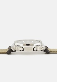Montre en métal avec un boîtier argenté, matériel noir et un bracelet tressé en kaki ; présente des bords polis et deux boutons latéraux pour la fonctionnalité.