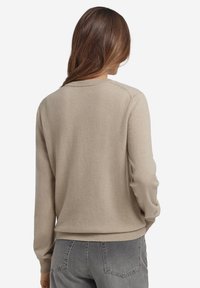 Beżowy sweter wykonany z miękkiej, teksturowanej tkaniny. Posiada długie rękawy, okrągły dekolt oraz ściągacze przy mankietach i na dole, zapewniające dopasowanie.