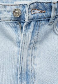 Svijetloplave traperice sa zatvaračem, metalnim dugmetom i kontrastnim šavovima. Materijal ima teksturirani, blago izblijeđeni izgled.