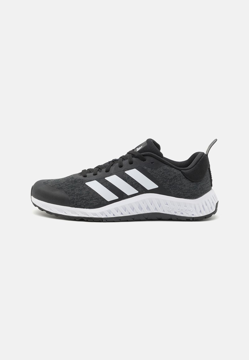 Black athletic shoe with textured upper, three white stripes, cushioned sole, and a pull tab on the heel for easy wear.