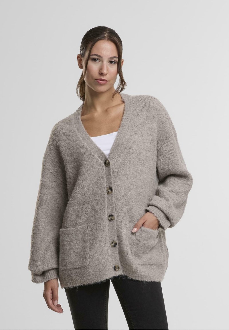 Svetlo siva pletena jopica z V-izrezom, dolgimi rokavi, sprednjimi žepi, gumbi po sredini in mehkimi, teksturiranimi zaključki.