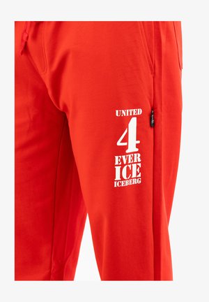 Pantalones de chándal rojos de algodón, con un diseño impreso en blanco que lleva el texto "UNITE 4 EVER ICEBERG" en la pierna izquierda.