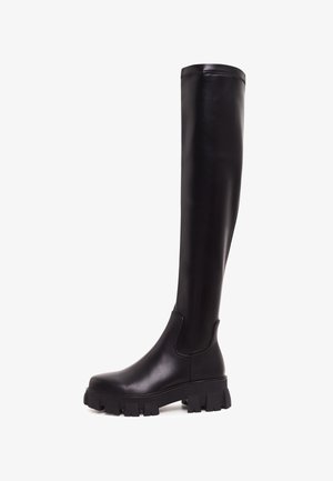 Bottes en cuir noir montant jusqu'aux cuisses, avec une semelle épaisse et une finition texturée. Présentent un design épuré et une fermeture éclair latérale pour un enfilage facile.