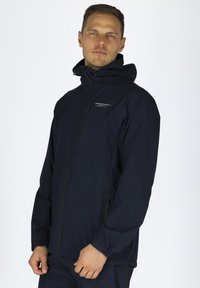 Marineblaue Regenjacke mit Reißverschluss, Stehkragen und zwei seitlichen Taschen. Hergestellt aus wasserabweisendem Material, mit einem minimalistischen Design.