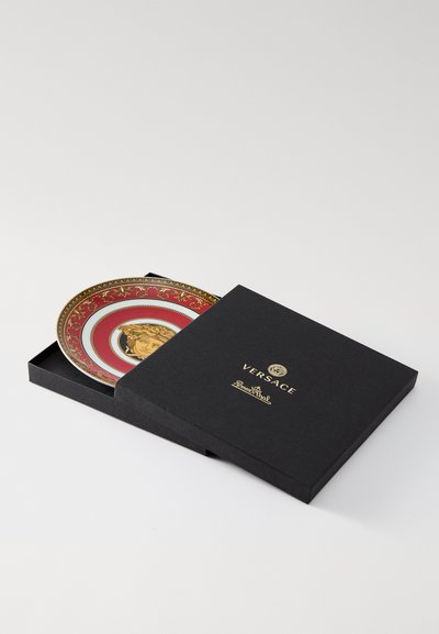 Διακοσμητικό πιάτο Versace με περίτεχνο κόκκινο και χ�ρυσό σχέδιο και κεντρικό μοτίβο. Παρουσιάζεται σε μαύρο κουτί με χρυσά γράμματα.