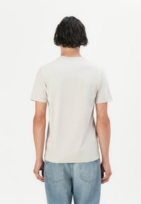 T-shirt gris clair à manches courtes avec un col rond, fabriqué en tissu doux. Présente une coupe régulière et un design simple, sans embellissements.