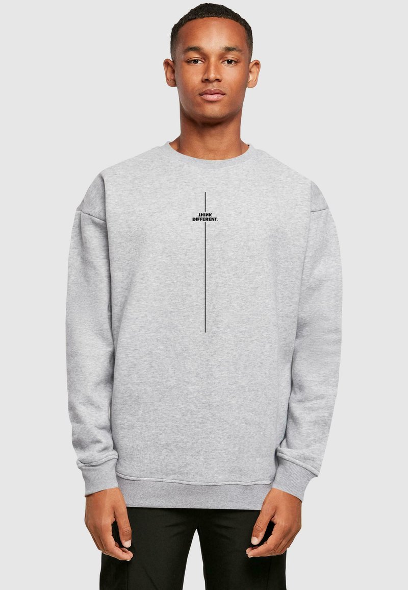 Grauer Sweatshirt mit langen Ärmeln, rundem Halsausschnitt und einem Frontdruck, der "DENK ANDERS." in Schwarz liest. Weicher Stoff mit gerippten Bündchen.