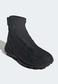 Bottes de randonnée noires imperméables avec une tige en textile lisse et une semelle en caoutchouc, dotées d'une fermeture éclair et d'accentuations renforcées pour plus de durabilité.