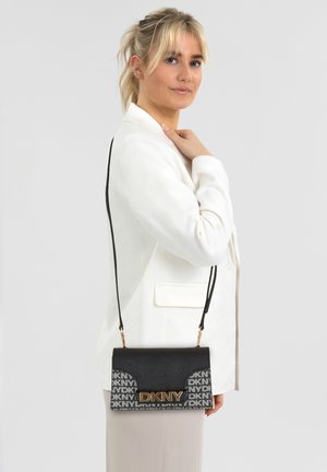 Schwarze DKNY Umhängetasche mit goldenem Logodetail, mit strukturiertem Finish und schwarzem Riemen, vor neutralem Hintergrund dargestellt.