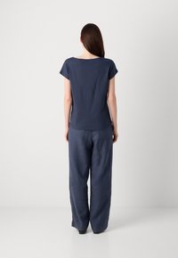 Navy blue cotton t-shirt with short sleeves and a rounded neckline, paired with loose-fitting navy blue linen trousers.