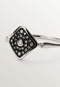 Anillo de plata con un engaste cuadrado adornado con diamantes, que presenta un diamante redondo central y acentos de banda pulida y suave.