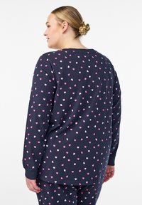 Pyjamatopp med långärmar i mörkblått bomull, med ett spritt mönster av rosa och vita hjärtan. Ribbstickade muddar och avslappnad passform.