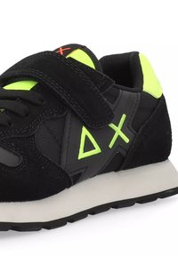 Sneaker nere con un design in suede e rete, dettagli in neon verde, cinturino in velcro e una suola in gomma robusta con motivo di trazione.