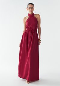 Langes burgunderfarbiges Neckholderkleid mit einem elastischen Bund, fließendem Rock und einem strukturierten Halsdesign. Glattes Material mit einer lässigen Passform.