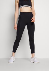 Schwarze hoch taillierte Leggings mit glattem Material, ausgestattet mit einer seitlichen Reißverschlusstasche und kombiniert mit einem passenden schwarzen Sport-BH.