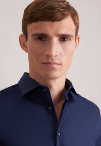 Navyblauw shirt met kraag en een gladde textuur, voorzien van een contrasterende, gemusterde binnenkraag en verborgen knopen.