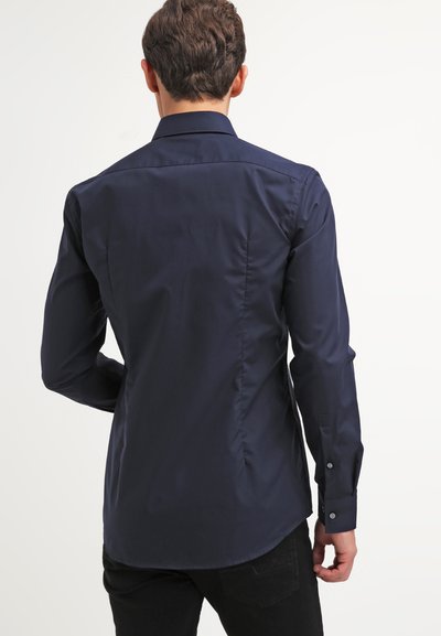 Chemise en bleu marine avec une texture lisse et brillante, dotée d'un col classique et de manches longues, coupe ajustée et poignets à boutons.