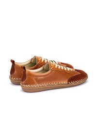 Zapatillas de cuero y ante en marrón claro con un diseño de cordones crema, bordes cosidos y suela de goma. Acabadas con un talón marrón oscuro.