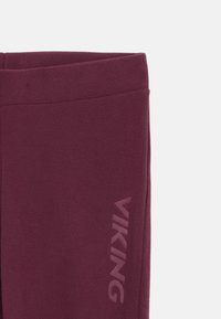 Tuvas skats uz bordo vilnas audumu, uz kura labajā pusē vertikāli ir drukāts vārds "VIKING" tumšākā krāsā.