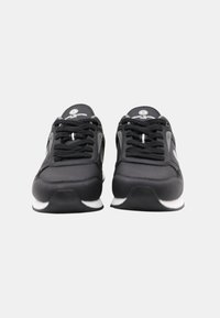 Baskets noires avec une texture en cuir lisse, semelle en caoutchouc blanche et accents gris ; avec des lacets plats et un design de bout arrondi.