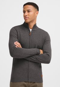 Dunkelgrauer Zip-Up-Pullover mit hohem Kragen, gerippten Bündchen und Saum. Verfügt über ein kleines Leder-Logo-Patch unten links.
