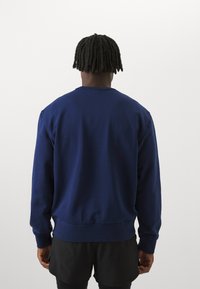 Felpa in cotone blu navy con polsini e orlo a costine, caratterizzata da un collo rotondo e una texture liscia. Vista posteriore senza motivi.