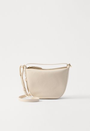 Pieni beige nahkainen olkalaukku, jossa on kullanvärinen vetoketju ja säädettävä hihna valkoisella taustalla.