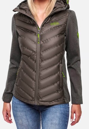 Woman wearing a gray hooded puffer jacket with knit sleeves and neon green zipper accents, paired with blue jeans.