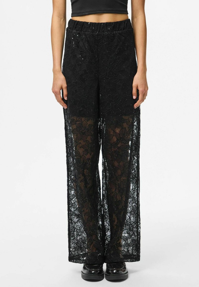 Crne čipkaste hlače imaju široke nogavice od prozirne tkanine, elastični struk i cvjetne uzorke. Pogodne za slojevito nošenje.