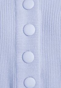 Světle modrá žebrovaná pletenina s pěti velkými hladkými knoflíky; má texturu s vertikálními pruhy a jemný pocit.