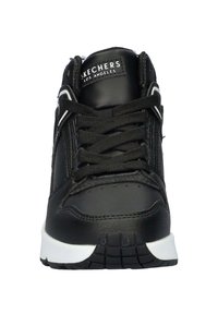 Zwarte sportieve schoen met een gladleren bovenwerk, vetersluiting, gewatteerde kraag en een witte zool met een geprofileerde grip. Voorzien van een logo op de tong.