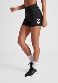 Zwarte sportshorts met een hoge tailleband, voorzien van witte chevronaccenten aan de zijkanten. Gladde textuur, ontworpen voor actieve kleding.