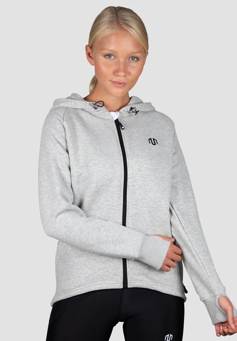 Svetlošedá mikina na zips s kapucňou, dlhými rukávmi a rebrovanými manžetami. Na hrudi má čierne logo a hladký povrch.