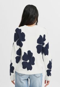 Weißer Pullover mit marineblauem Blumenmuster, langen Ärmeln und Rundhalsausschnitt. Weicher Stoff mit lässiger Passform, sichtbaren Nähten und gerippten Bündchen.