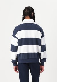 Sudadera de algodón con rayas horizontales en azul marino y blanco, de corte relajado y puños acanalados. Presenta un cuello clásico y hombros caídos.