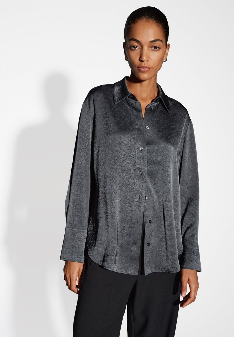 Camicia button-up grigia scura, con texture, colletto, motivo discreto e maniche lunghe. Chiusura frontale con bottoni e vestibilità comoda.