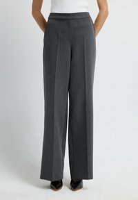 Pantalones de pierna ancha grises, ajustados, con frente plano, rayas verticales y bolsillos. Tejido de lana suave, terminado con un dobladillo limpio.