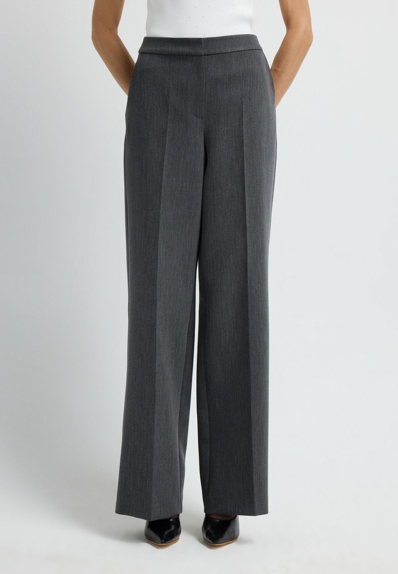 Pantalones de pierna ancha grises, ajustados, con frente plano, rayas verticales y bolsillos. Tejido de lana suave, terminado con un dobladillo limpio.