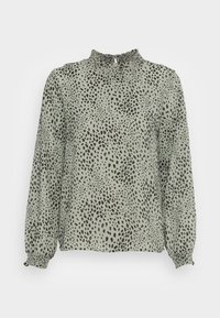Blusa verde con un alto escote con fruncidos, mangas largas abullonadas y un patrón de manchas negras en toda la prenda. Tejido ligero y texturizado.