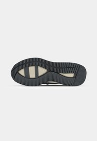 Shoe sole with a multi-patterned black rubber design, featuring beige accents and a textured surface for grip and durability.