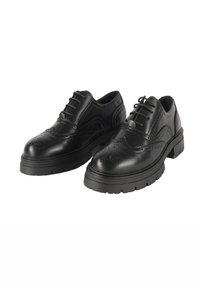 Le scarpe brogue in pelle nera presentano un design decorativo a punta d'ala, una superficie testurizzata, lacci e una suola spessa in gomma per stabilità.